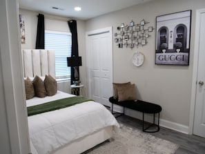 A bedroom with a bed, a bench, a wall clock, and a framed picture. - Luxury Home 5 min Uptown Charlotte Chic Glam Clt (Charlotte)