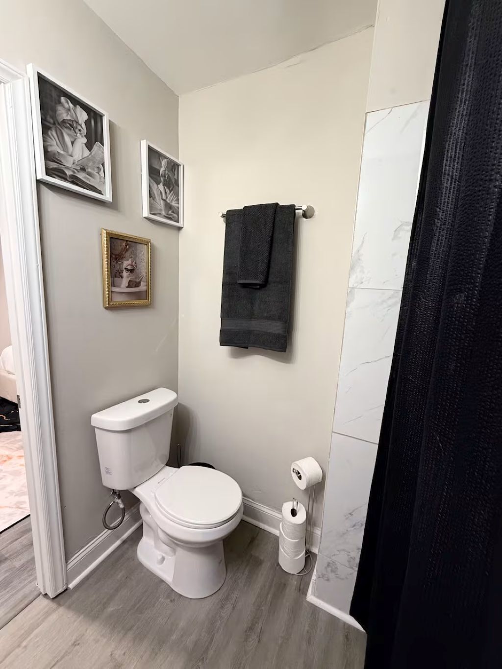 A bathroom with a toilet, a towel rack, and framed pictures on the wall.