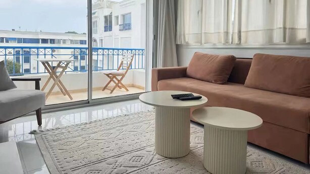 Un salon moderne avec un canapé, une table basse et un balcon agrémenté d’une chaise.