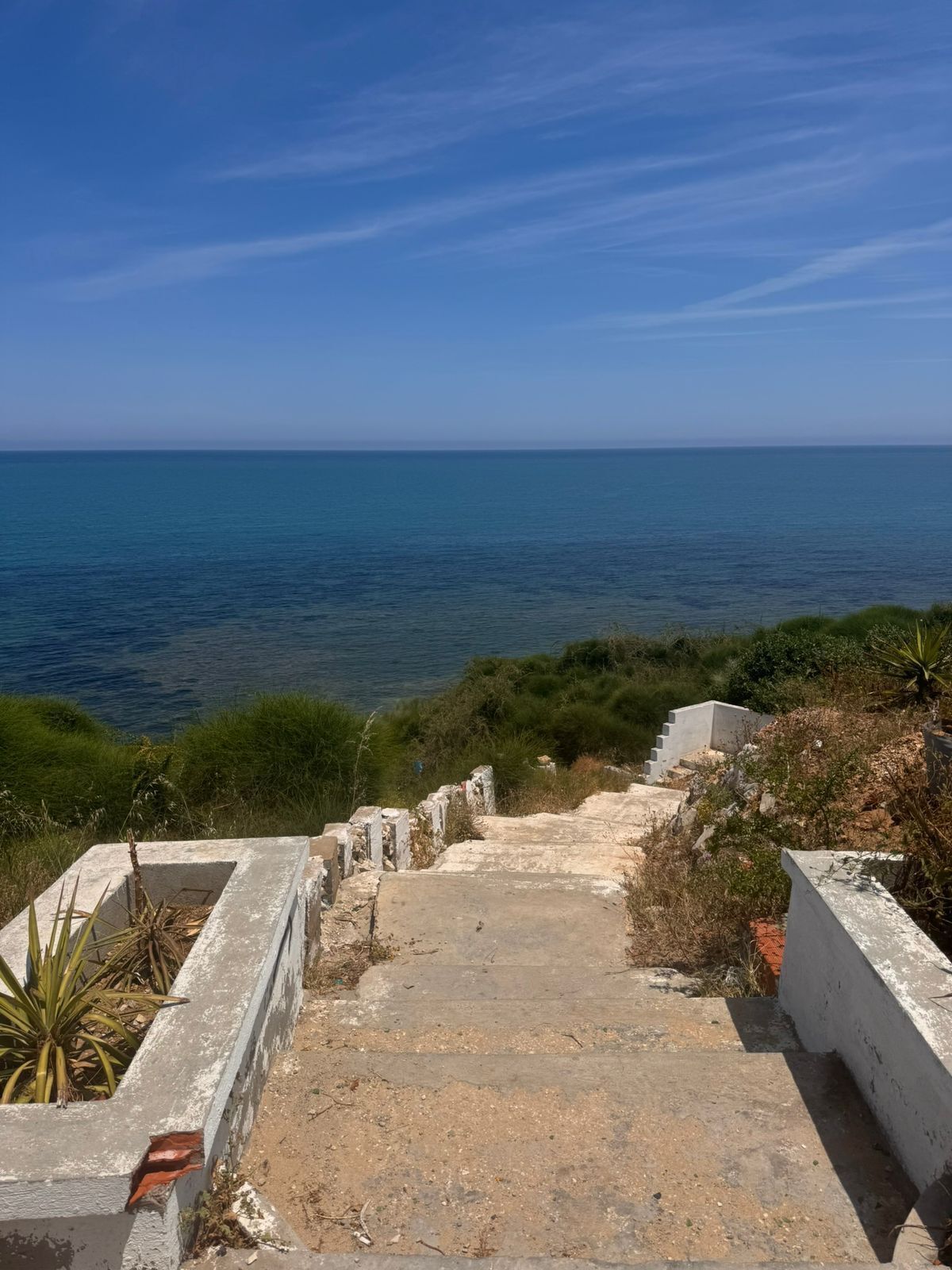 Un escalier en béton menant à une zone côtière offrant une vue sur la mer.