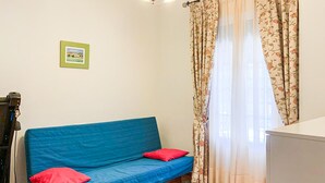 A room with a blue sofa, red cushions, a framed picture on the wall, and floral curtains. - 3 bedroom lovely home in Cantillana (Cantillana)