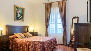 A bedroom with a bed, a nightstand, a dresser, a mirror, a painting, and a window with curtains. - 3 bedroom lovely home in Cantillana (Cantillana)