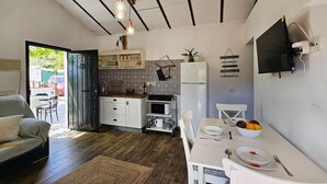 A compact kitchen with white cabinets, a microwave, and a dining area with a table set for two. - Amazing home in Yunquera (Yunquera)