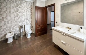 A bathroom with a tiled wall, a wooden door, a white sink, and a mirror. - Amazing home in La Celada (La Celada)