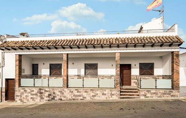 A two-story building with a tiled roof, a balcony with a metal railing, and a stone facade. - Amazing home in La Celada (La Celada)