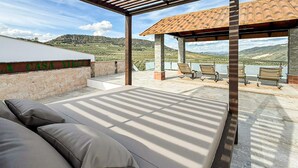 En utomhusplats med sittmöbler, en pergola, en soffa och utsikt över en vingård.