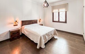 A bedroom with a bed, nightstands, a window with curtains, and a hanging light fixture. - Amazing home in La Celada (La Celada)