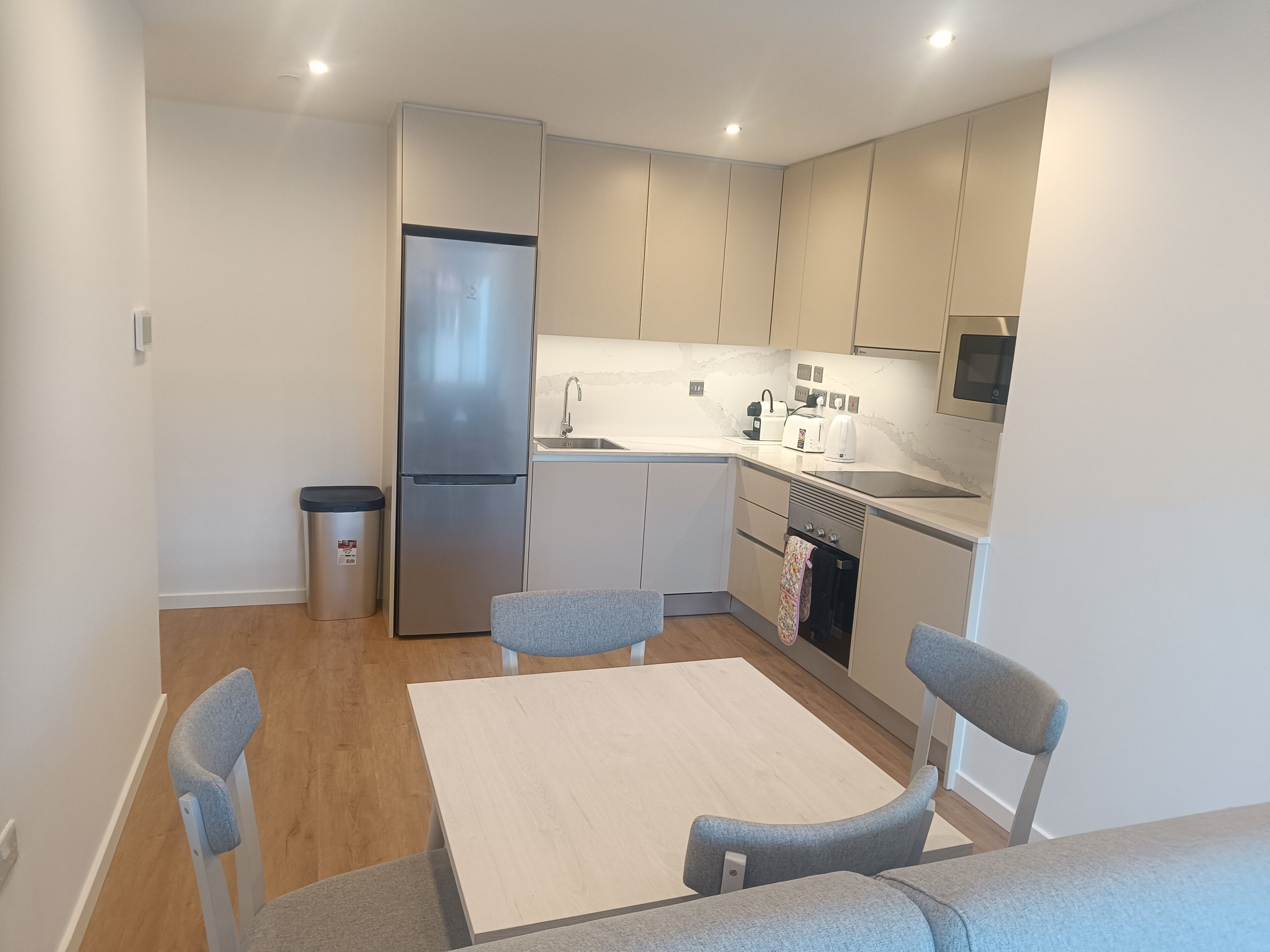 Cocina compacta con refrigerador, pileta y microondas. Hay una mesa de comedor con cuatro sillas.