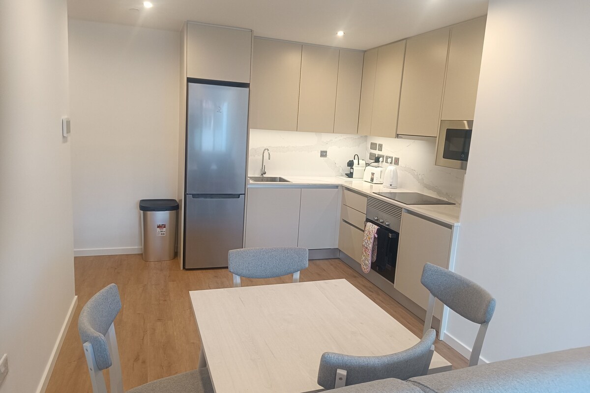 Cocina compacta con refrigerador, pileta y microondas. Hay una mesa de comedor con cuatro sillas.
