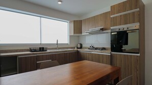 Eine moderne Küche mit Holzausstattung, einem Edelstahlbackofen und einem großen Fenster.