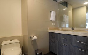Une salle de bain comprenant des toilettes, un lavabo avec un miroir et un meuble avec des tiroirs.