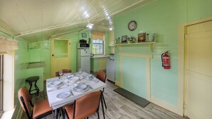 Een eetruimte met een tafel voor vier personen, een keuken op de achtergrond en een brandblusser aan de muur.