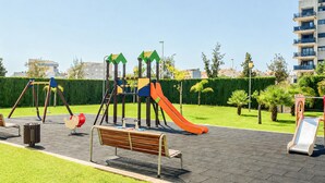 Ein Spielplatz mit Schaukeln, einer Rutsche und einer Bank.