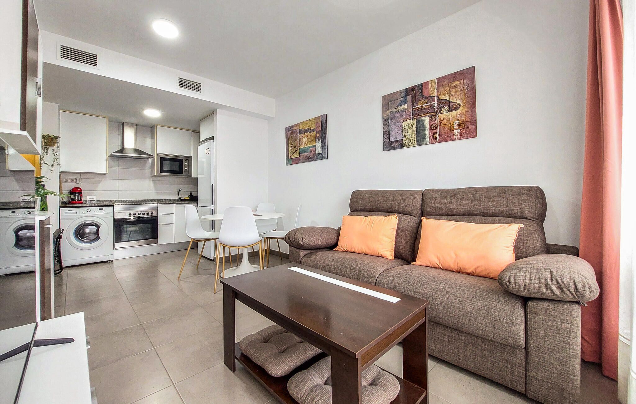 A modern living room with a sofa, a coffee table, and a kitchen in the background.