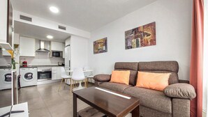 Ein modernes Wohnzimmer mit einer Couch, einem Couchtisch und einer Küche im Hintergrund.