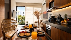 A modern kitchen with a dining table set for breakfast, including waffles, strawberries, and orange juice.