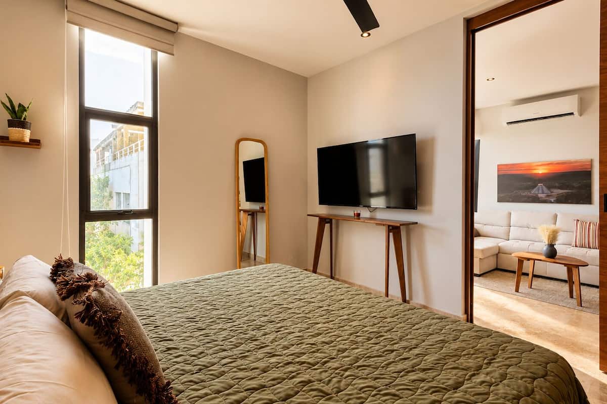 Un dormitorio moderno con una cama grande, un televisor, un cuadro y vistas al exterior.