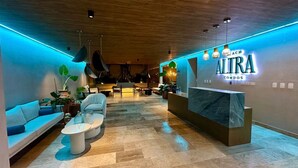 A modern reception area with a reception desk, seating area, and potted plants.