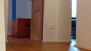 Käytävä, jossa on puulattia, puuovi ja sininen seinä.