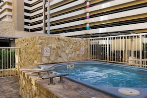 A hot tub with a 3 ft depth sign, surrounded by stone walls and metal railings, with a no diving sign and a caution wet floor sign. - 7 nights at Waikiki Beach Walk, 2-BR Deluxe Condo, 7/30-8/5, Steps From Ocean (Honolulu)