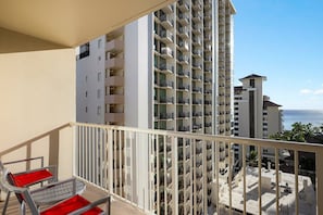 A high-rise building with multiple balconies, a clear view of the ocean, and a red chair on the balcony. - 7 nights at Waikiki Beach Walk, 2-BR Deluxe Condo, 7/30-8/5, Steps From Ocean (Honolulu)