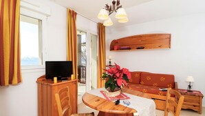 Una sala acogedora con un mueble de televisión de madera, una mesa redonda de comedor y un sofá.