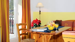 A dining area with a wooden table, chairs, a potted plant, and a lamp. - Appartement duplex à quelques pas du centre (Font Romeu)