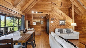 A wooden cabin interior with a dining area, sofa, and a kitchen. - Elianah's Cabin & Maggie's Cabin by Avantstay 2 Cabins + 2 Hot Tubs + Fire Pit Long-range Smokies Views 9 Min to Cades Cove + Townsend (Townsend)