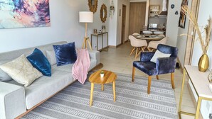 Ein Wohnzimmer mit einer Couch, Sesseln, einem Couchtisch und einem Essbereich mit Tisch und Stühlen.