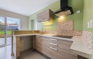 A kitchen with a built-in stove, wooden cabinets, and a tiled backsplash. - Beautiful family home (Rives de l'Yon)