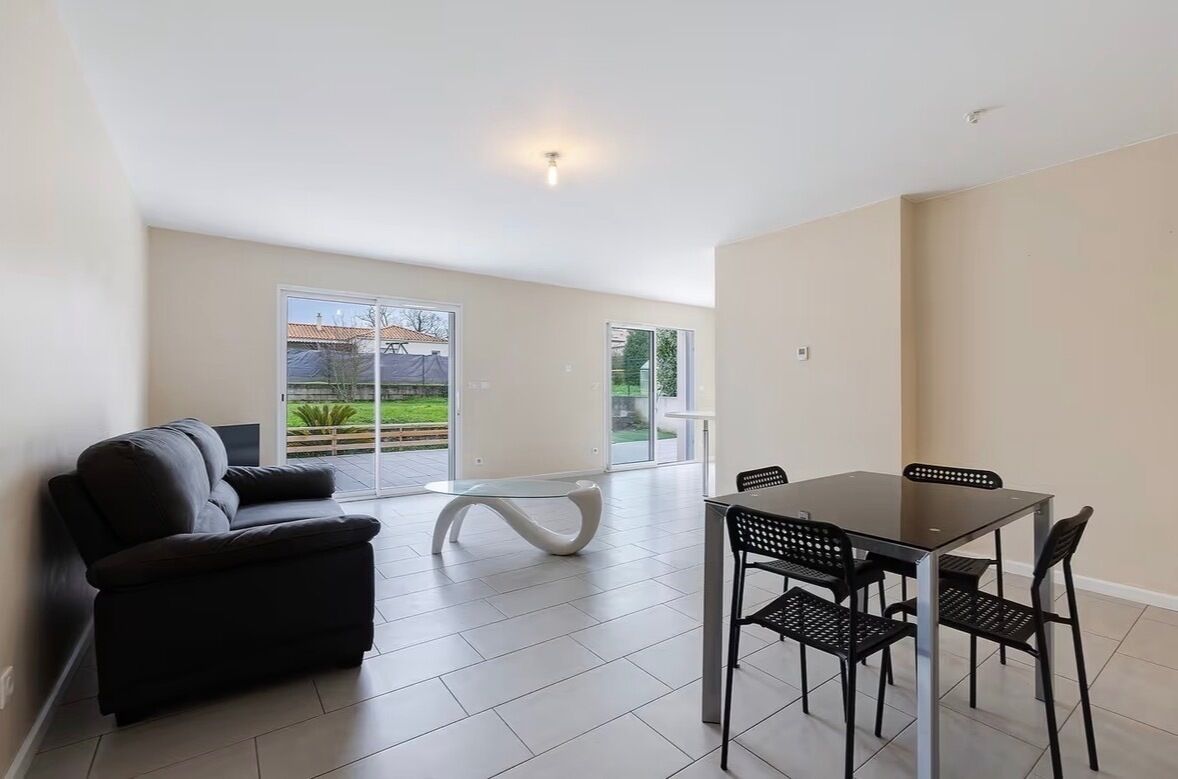 A modern living room with a sofa, a glass-top table, and a dining table with chairs.