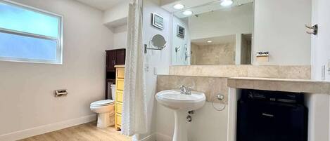 A bathroom with a toilet, sink, and dishwasher.