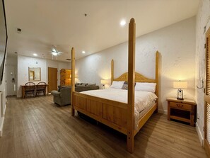 A bedroom with a four-poster bed, a desk with chairs, a sofa, and a bedside table with a lamp. - Amira Resort #17 | Studio | Near Pools and Pickleball! (Saint George)