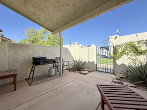 An outdoor patio area with a grill, a bench, and a gate leading to a building. - Amira Resort #17 | Studio | Near Pool & Pickleball (Saint George)