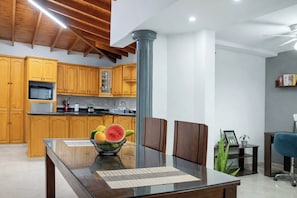 A modern kitchen with wooden cabinets, a glass dining table, and a central column.