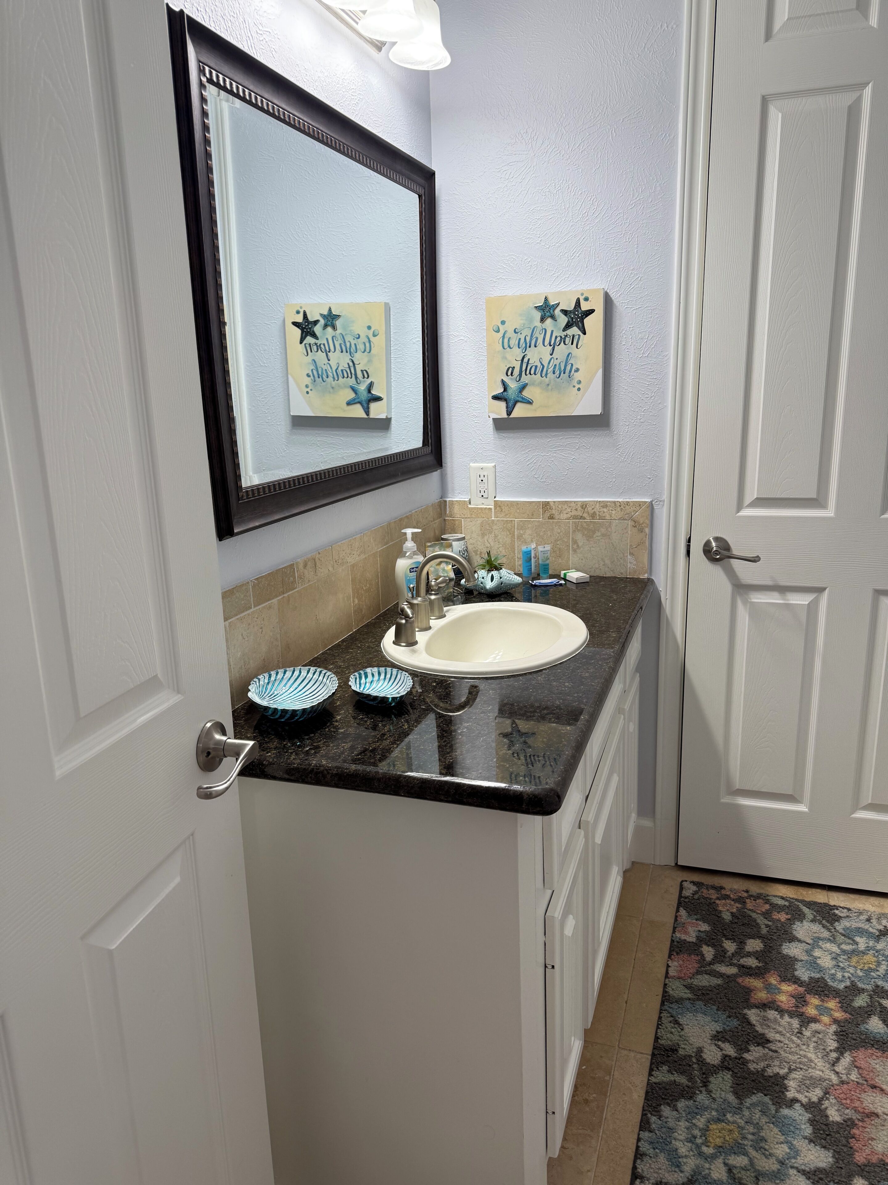 A bathroom with a white sink, a mirror, and two star-themed wall decorations.