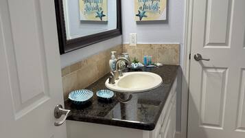 A bathroom with a white sink, a mirror, and two star-themed wall decorations.