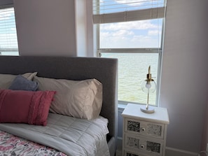 A bed with a grey headboard, a floral bedspread, and a nightstand with a lamp and decorative drawer. - Delightful 3-bedroom condo in charming Willis (Willis)