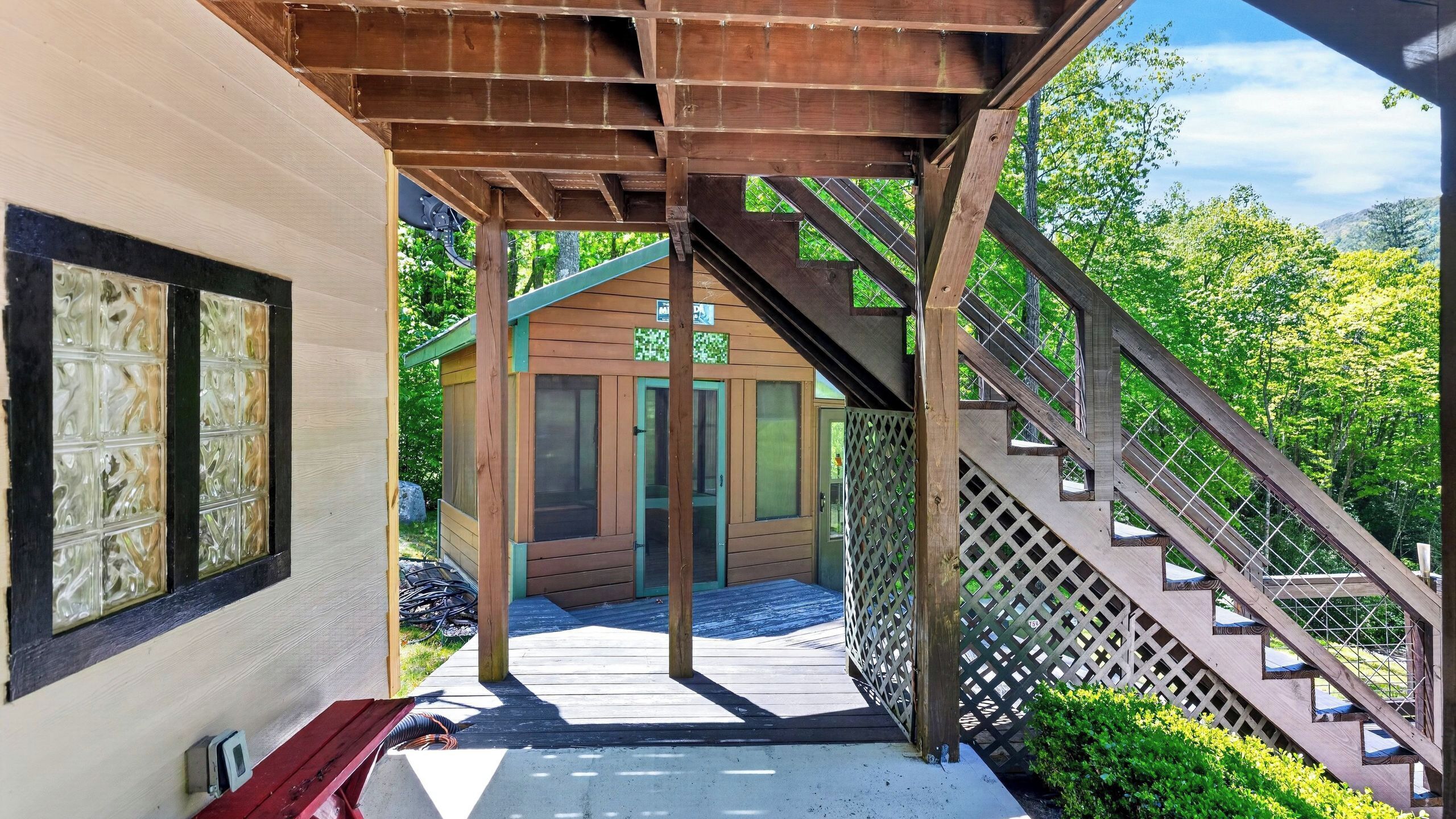 Une structure en bois avec un escalier menant à une porte, un banc et une vue sur la verdure.
