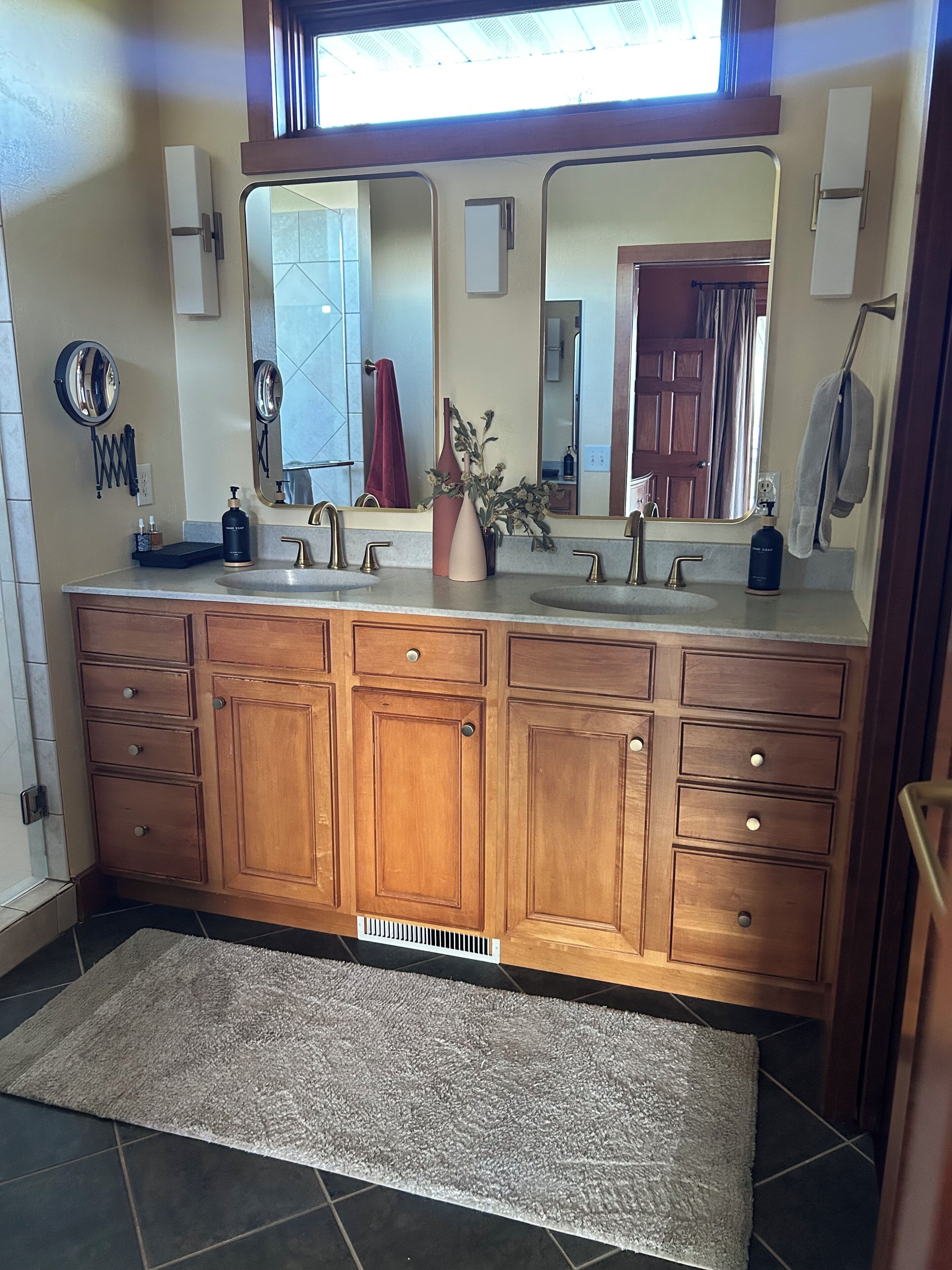 A bathroom with a wooden vanity, two sinks, a large mirror, and a towel rack.