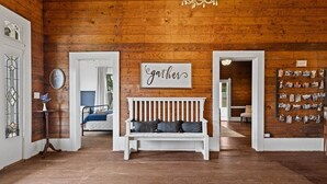 A wooden interior with a white bench, a wall-mounted sign, and a photo display. - The Anna Bell Suite at historic Jeter Farmhouse (Gladewater)
