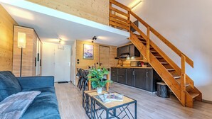 Uma sala de estar moderna com escada de madeira, área de jantar e cozinha.