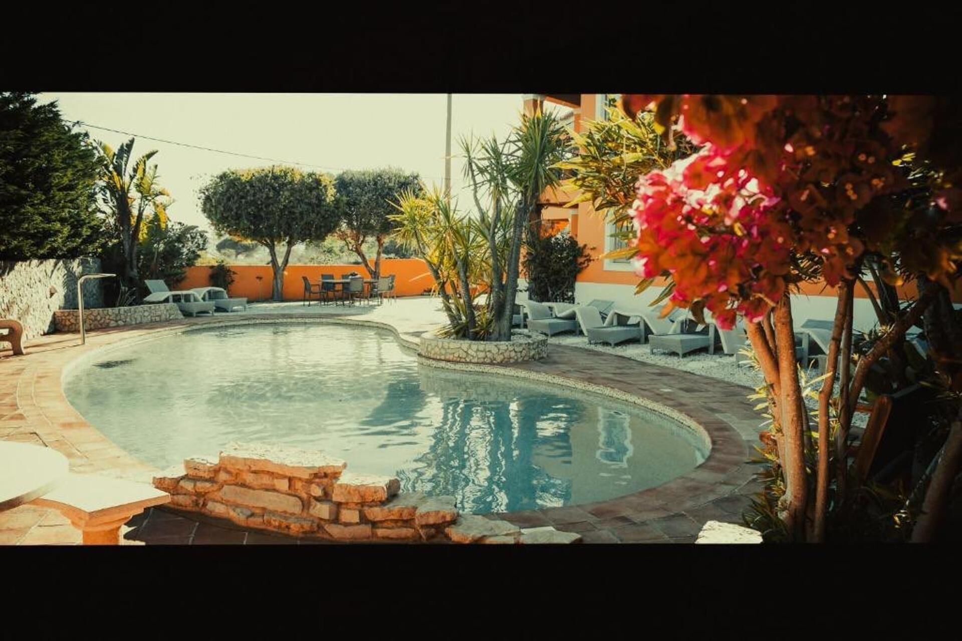 A swimming pool with lounge chairs and a stone wall.