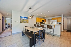 Une cuisine moderne dotée d’un îlot central, de meubles en bois et d’un coin repas avec une banquette.