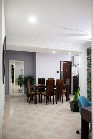 A dining area with a table and chairs, a potted plant, and a blue chair.