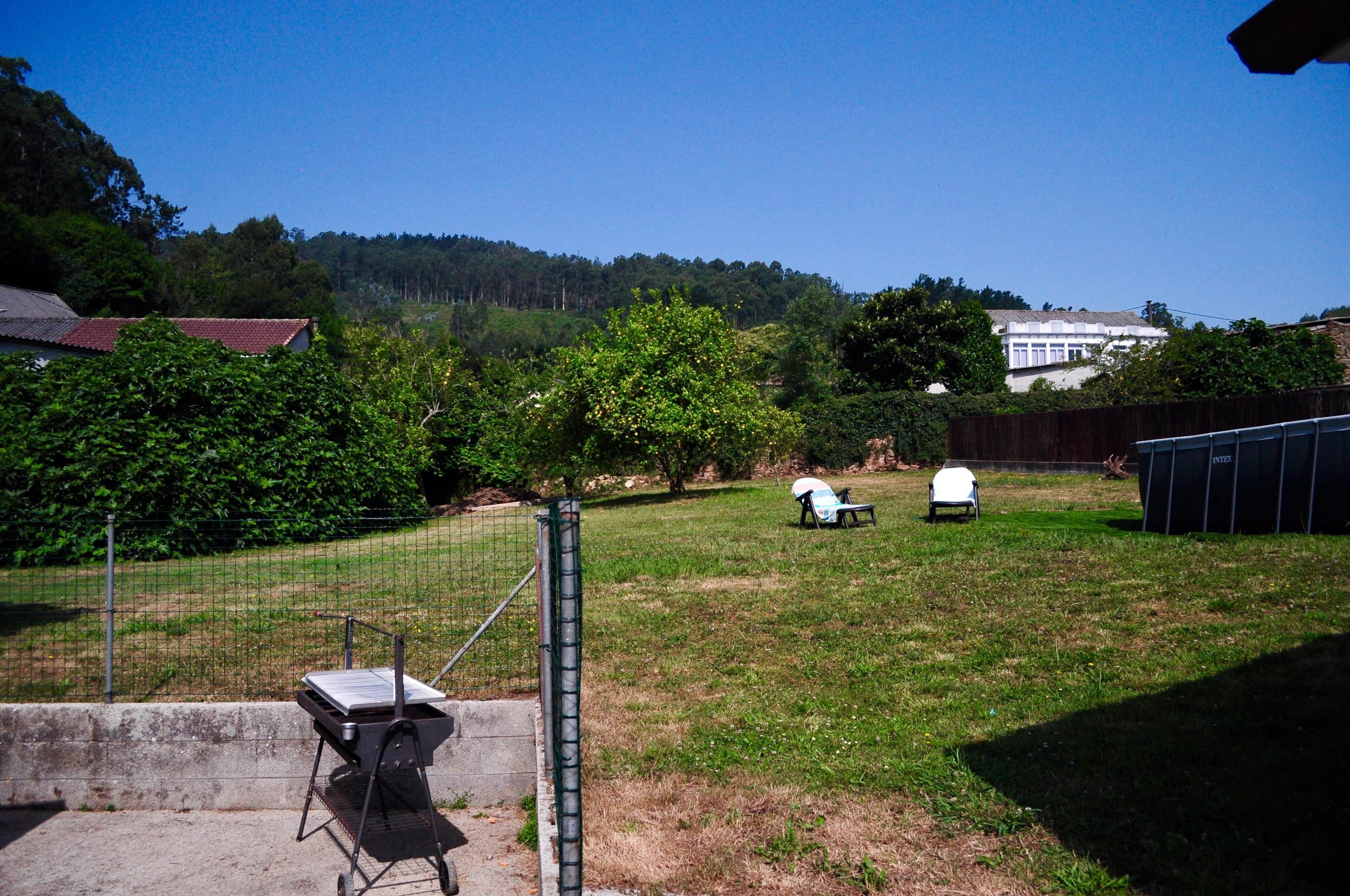 Un jardin avec un barbecue, une chaise blanche et une table de pique-nique.