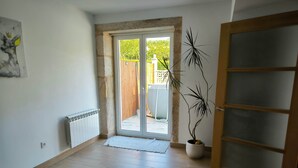 Habitació amb sòl de fusta, un radiador, una porta amb panells de vidre mat i una planta en test.