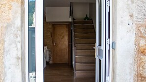 Un interior modern amb una escala que condueix a un segon pis, una porta amb un panell de vidre i una paret de pedra.