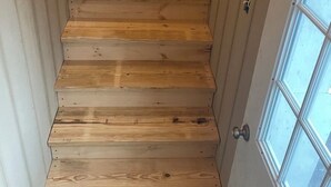 A wooden staircase leading to a door with a window. - Stylish 4BR Loft • Sleeps 8 • Prime Location (Oswego)