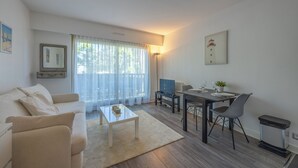 A modern living room with a sofa, coffee table, dining table, and chairs. - Studio des Ouvres - Welkeys (Deauville)